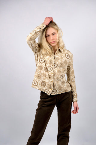 Cremefarbene 70s Bluse mit tollem Boho-Blumenmuster in Beige und Braun, die Größe entspricht ca. einer heutigen M bei einer für die 70s typischen figurbetonten/engen Passform – für einen eher lockeren Look empfehlen wir die Bluse aber einer XS oder S – bitte Maße beachten