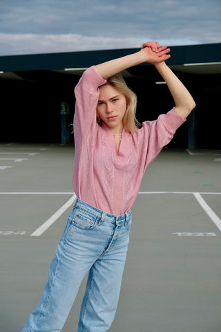 80s Pullover in lockerem Schnitt mit halblangen Ärmeln und V-Kragen, die Farbe ist ein helles Rosa mit silbernen Glitzerfäden – wir empfehlen den Pullover einer XS bis S je nach gewünschter Passform